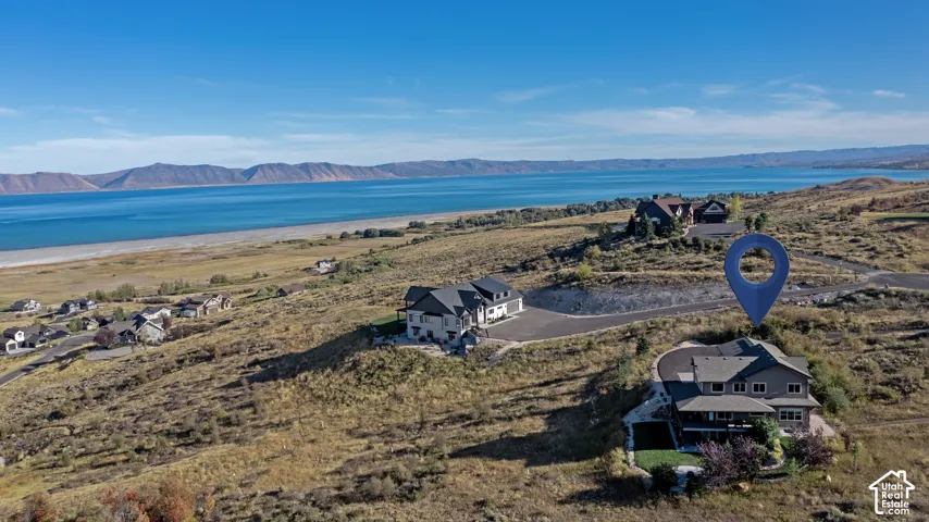 Elevated property with a large deck overlooking a body of water and distant mountains