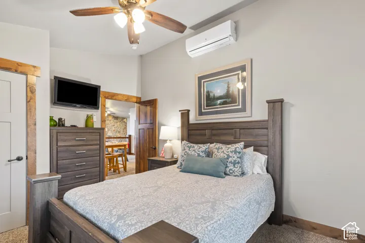 Bedroom with a wall unit AC, ceiling fan, and lofted ceiling