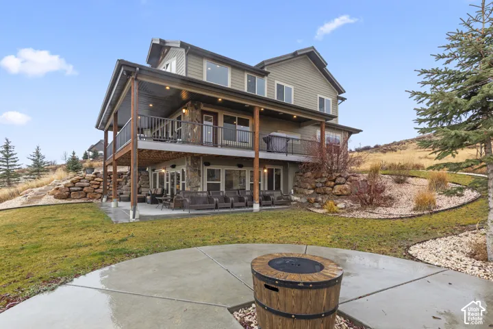 Back of property featuring a patio, stone siding, and a yard