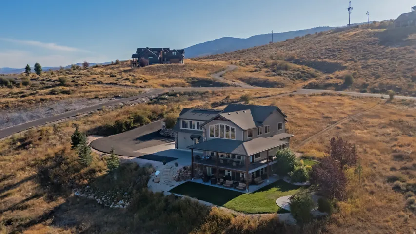 Multi-level residence featuring an expansive lower-level patio, a covered upper-level balcony, and a prominent arched window