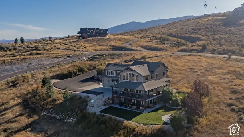 Multi-level residence featuring an expansive lower-level patio, a covered upper-level balcony, and a prominent arched window