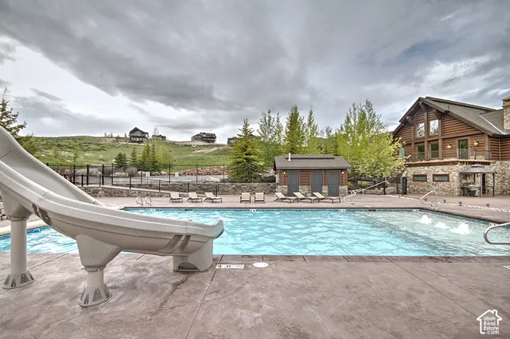 Community pool with a water slide and a patio