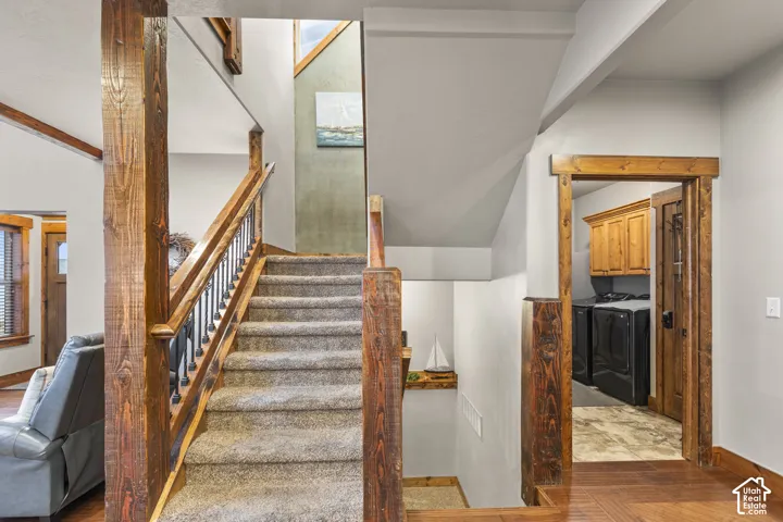 Stairs featuring washer and dryer and parquet floors
