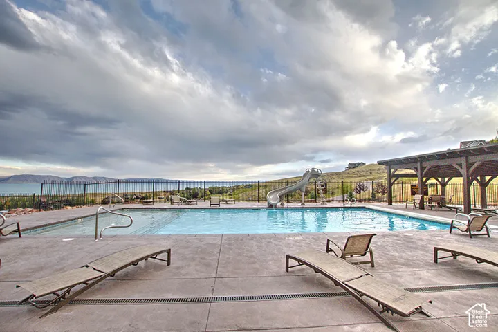 Community pool with a water slide, a patio area, a pergola, and a mountain view