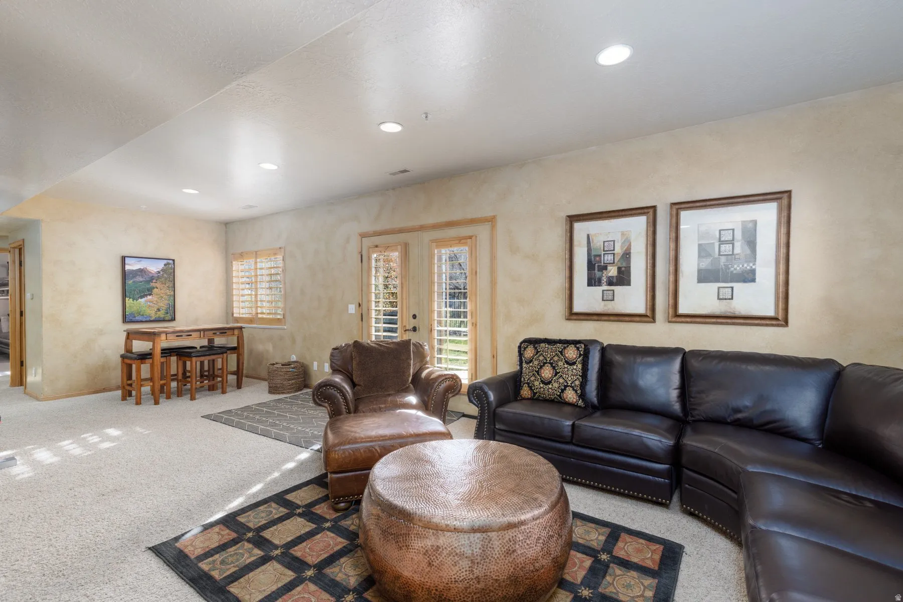 Carpeted living area with recessed lighting and french doors