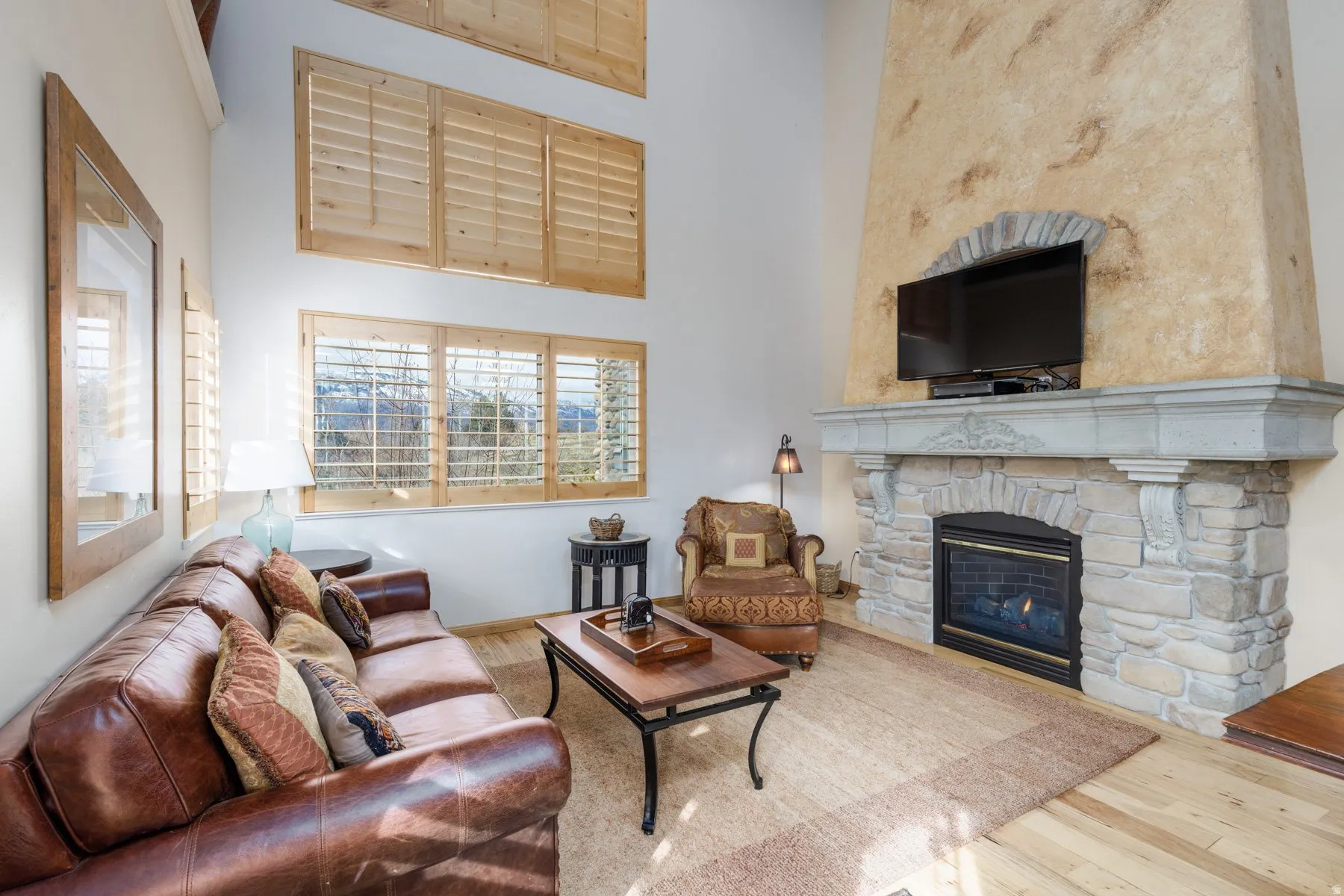 Living area featuring a high ceiling, wood finished floors, and a fireplace