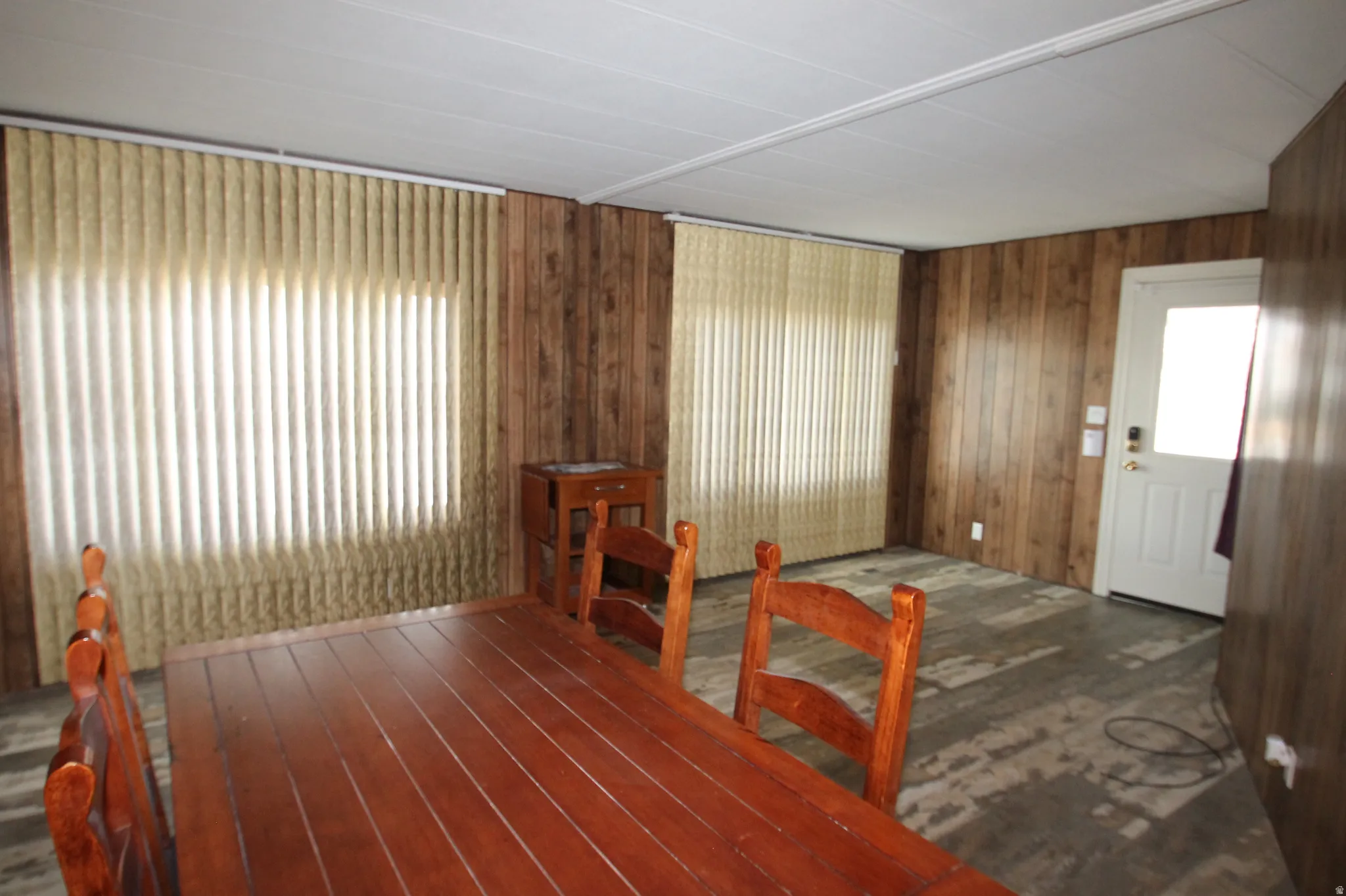 Dining space featuring dark wood-style flooring, wooden walls, and healthy amount of natural light