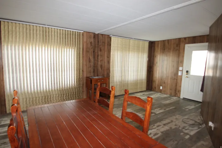 Dining space featuring dark wood-style flooring, wooden walls, and healthy amount of natural light