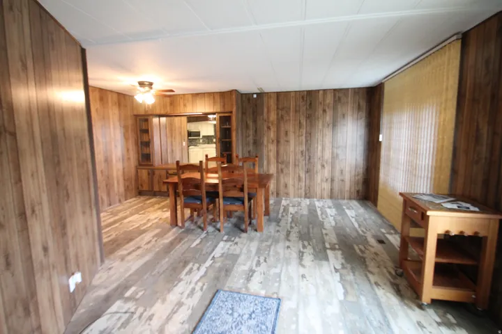 Dining area with wood walls, light wood-type flooring, and ceiling fan