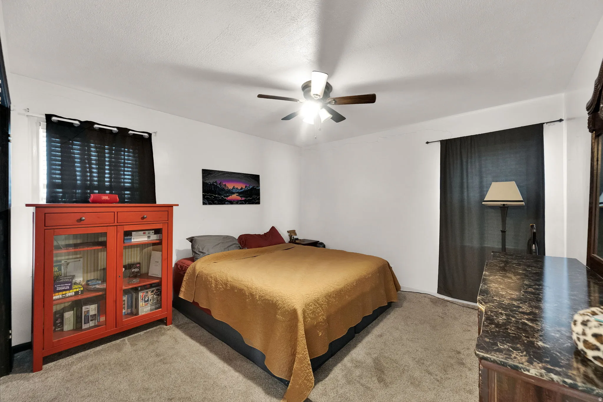 Bedroom with light colored carpet, ceiling fan, and a textured ceiling