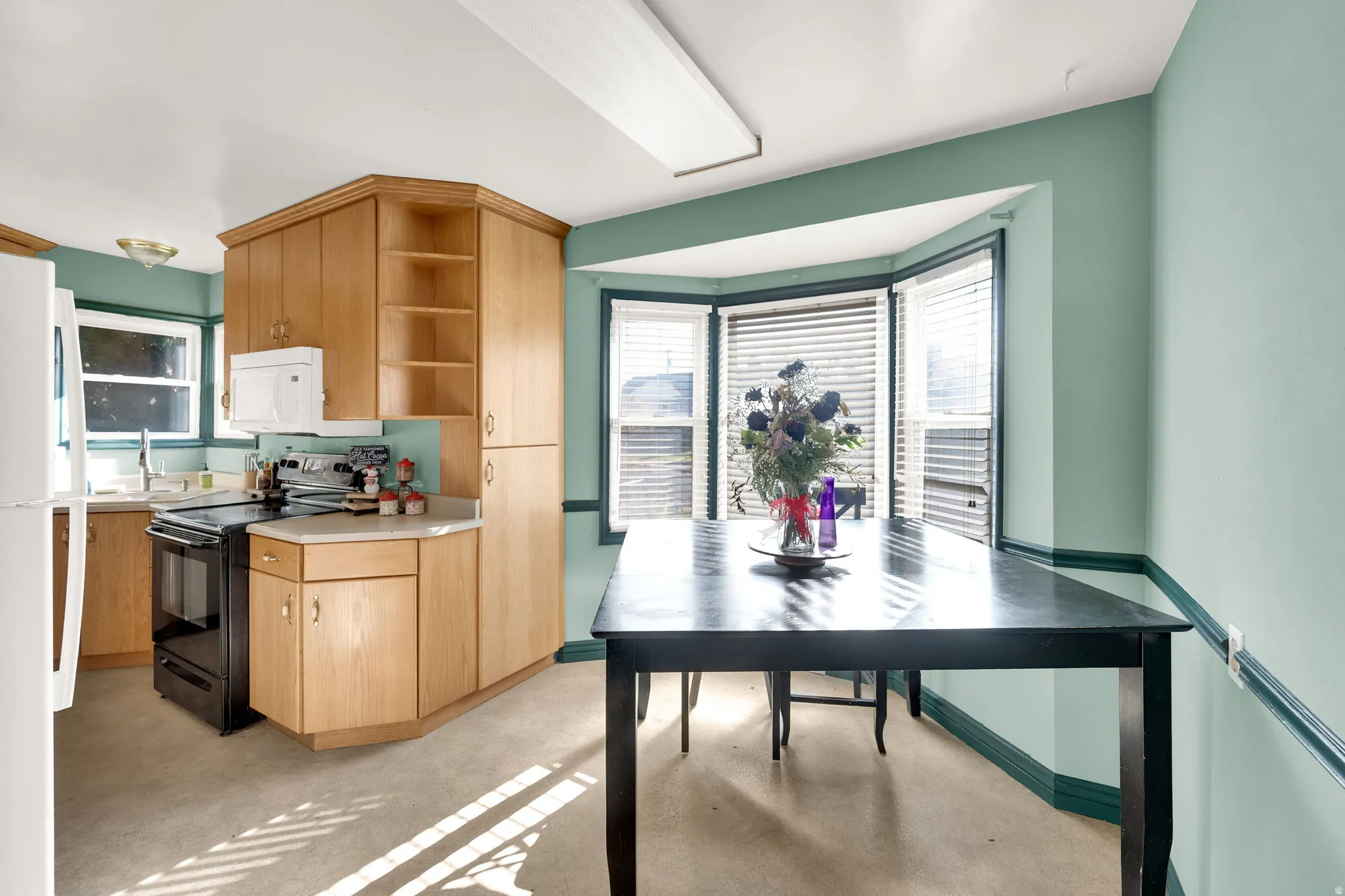 Kitchen featuring light countertops, finished concrete flooring, white appliances, open shelves, and plenty of natural light