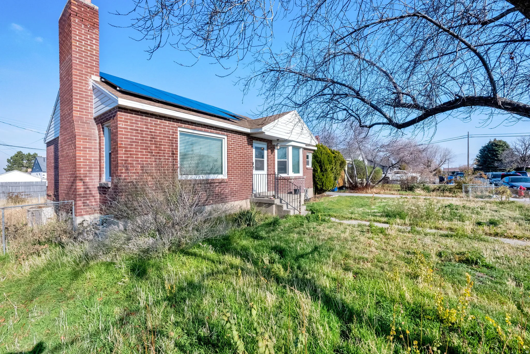 View of home's exterior featuring a chimney, solar panels, and brick siding