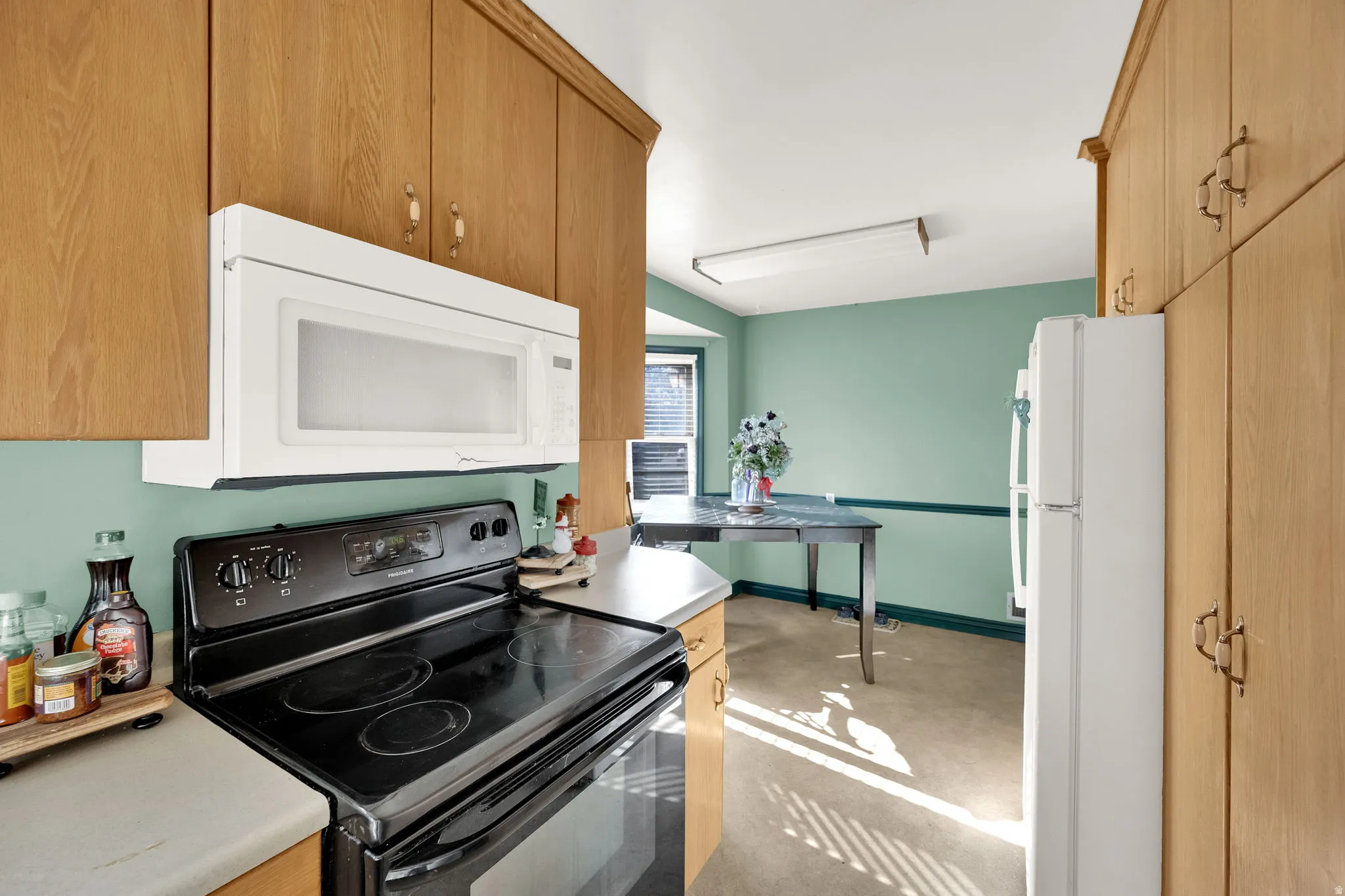 Kitchen with white appliances, light countertops, and light carpet