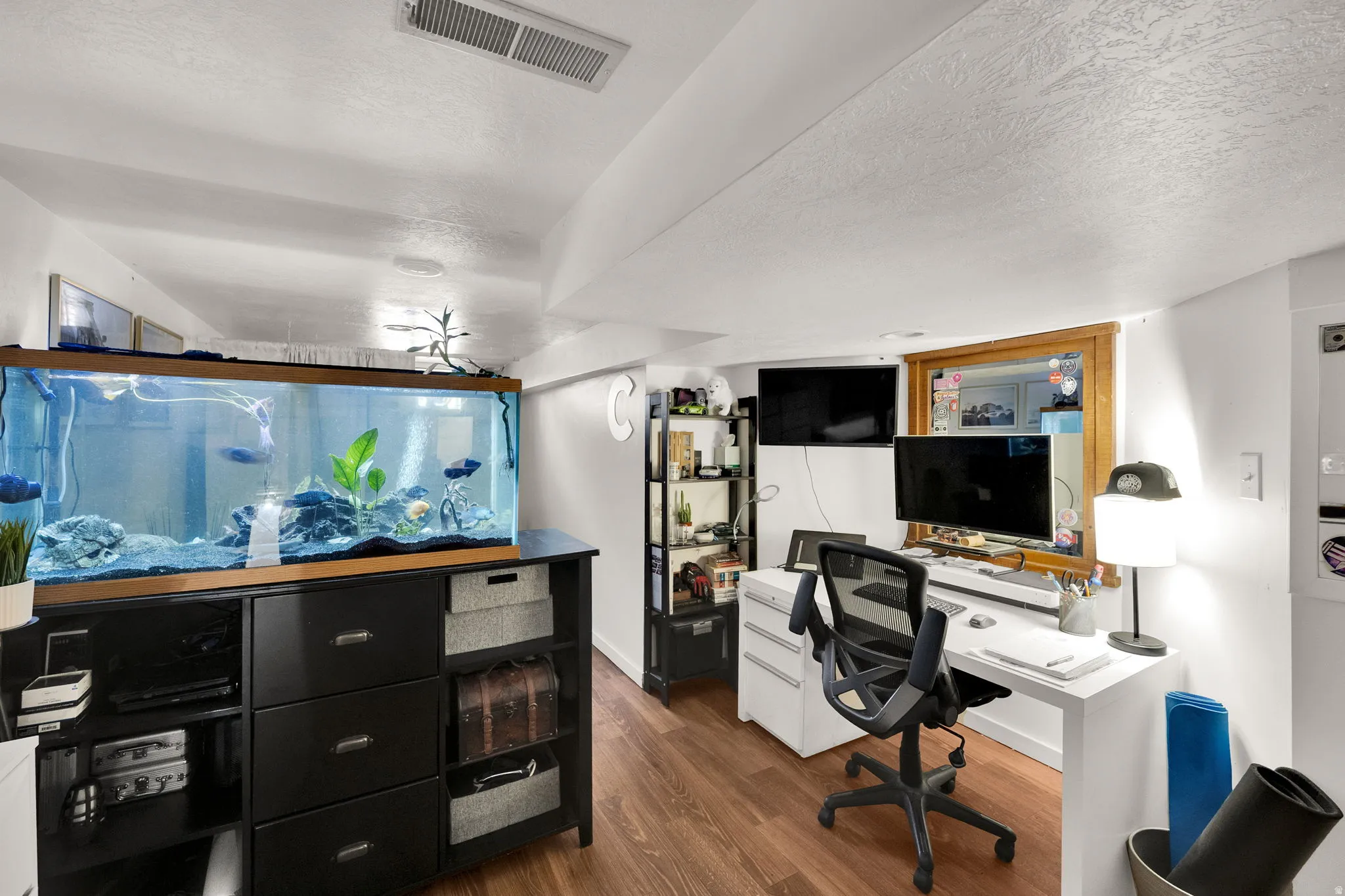 Home office with dark wood-type flooring and a textured ceiling