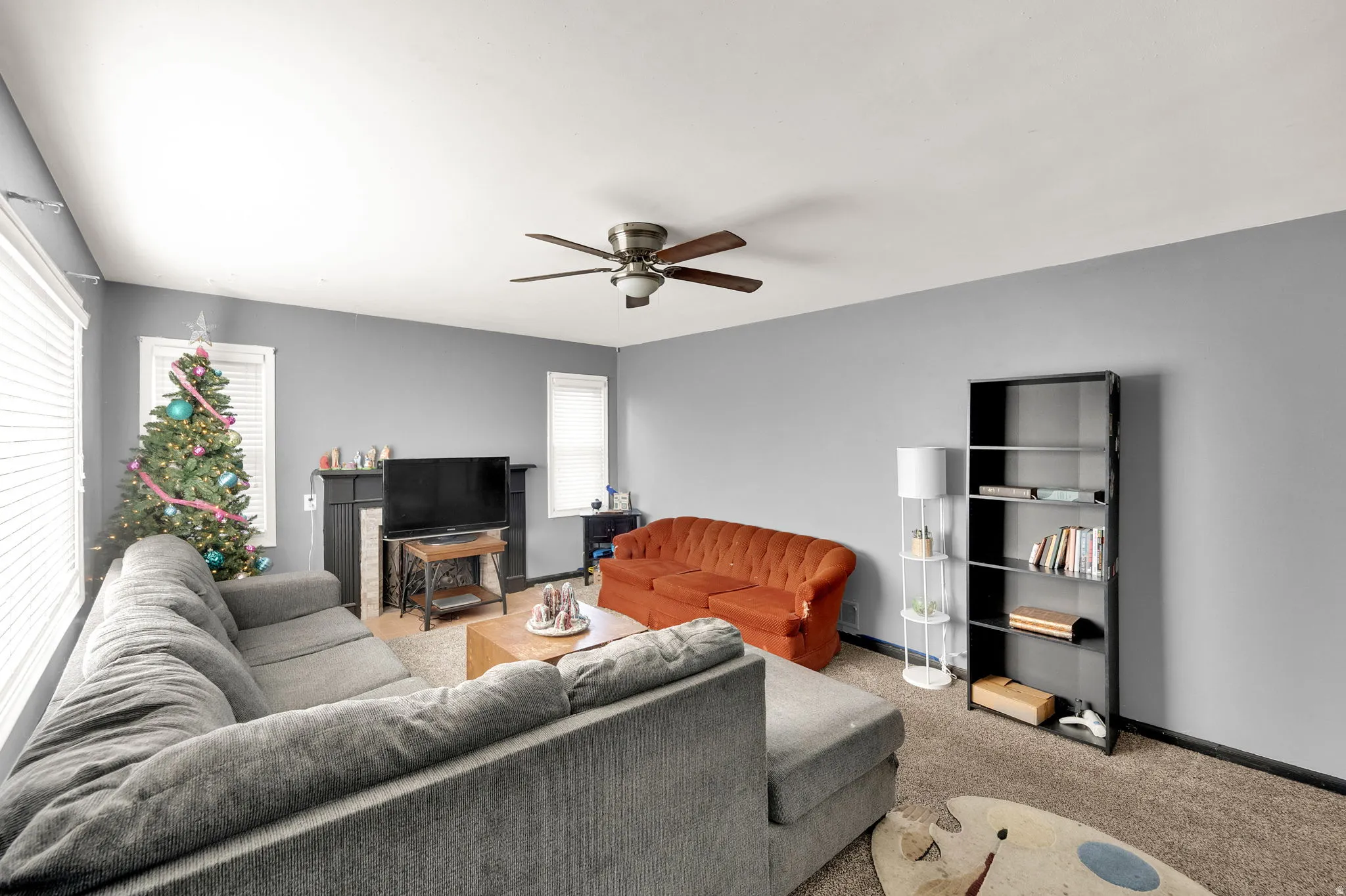 Carpeted living room with ceiling fan and baseboards