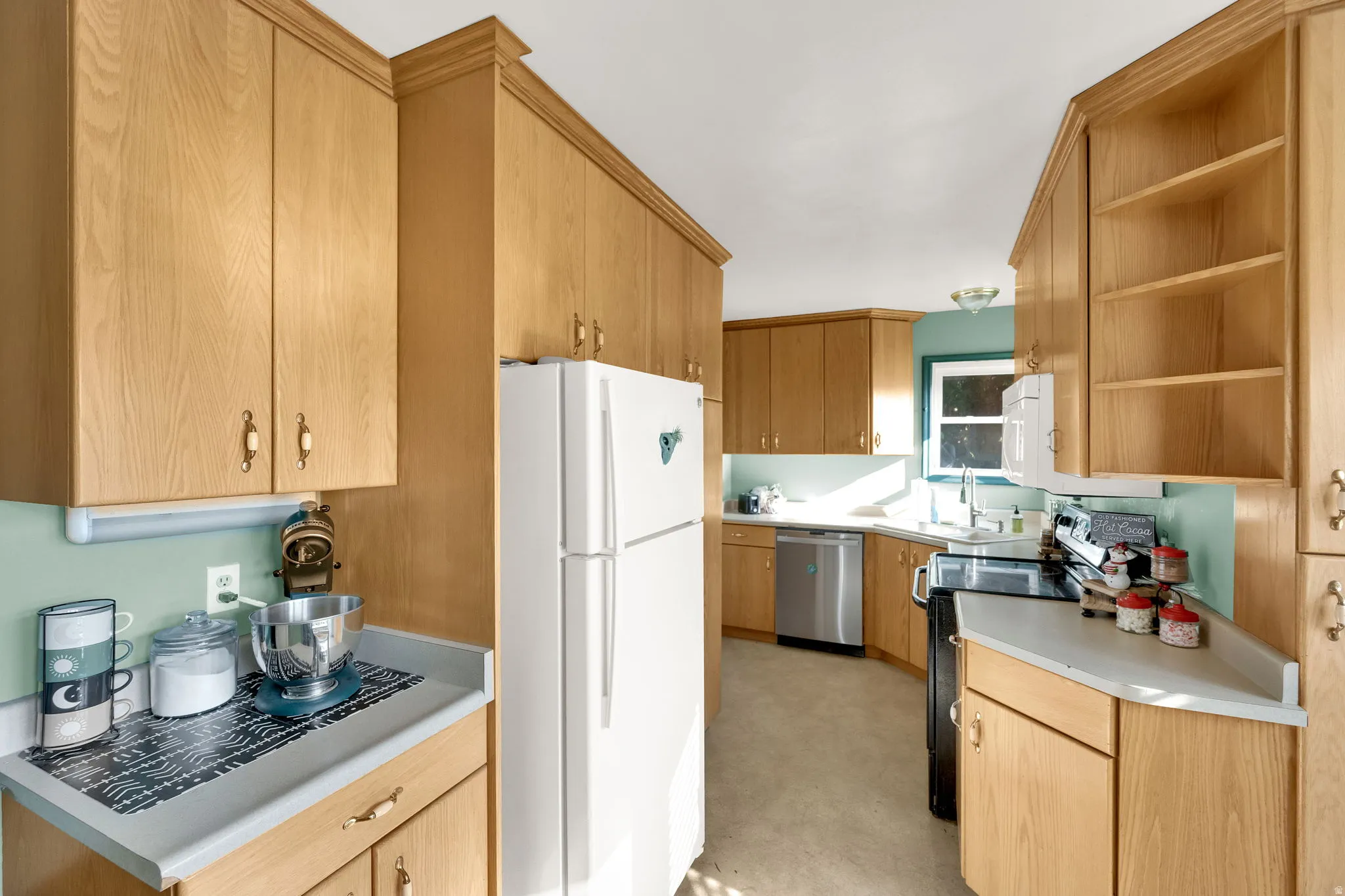 Kitchen featuring open shelves, white appliances, light countertops, and light brown cabinetry