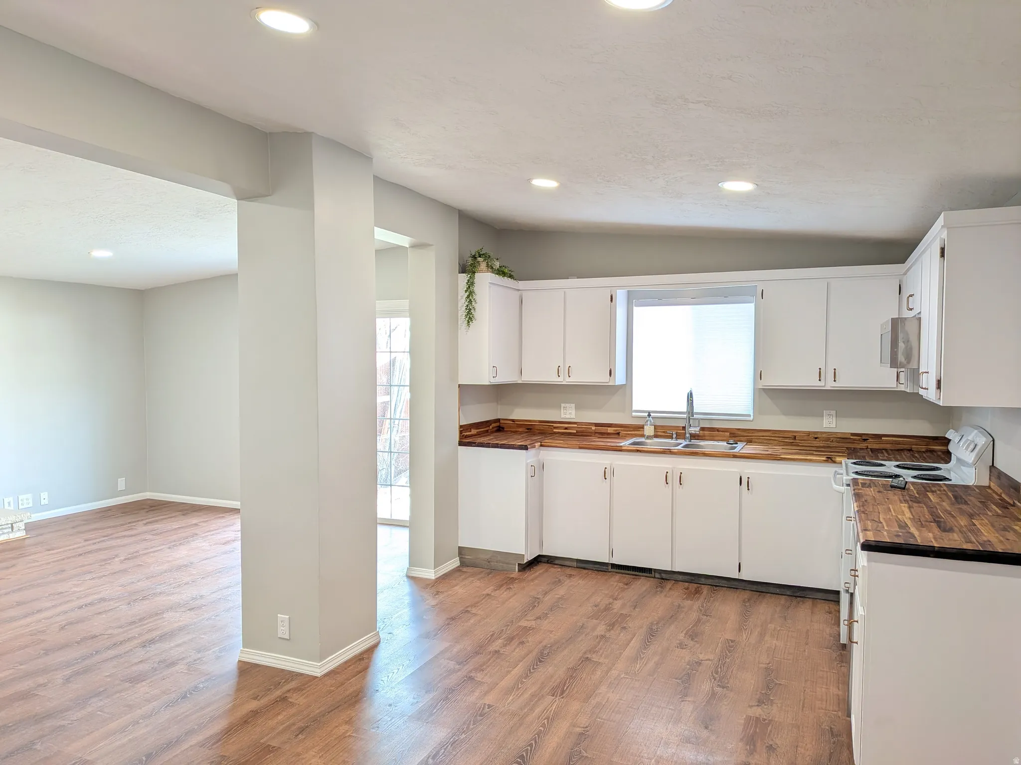 Kitchen with light wood-style floors, white cabinets, healthy amount of natural light, and recessed lighting