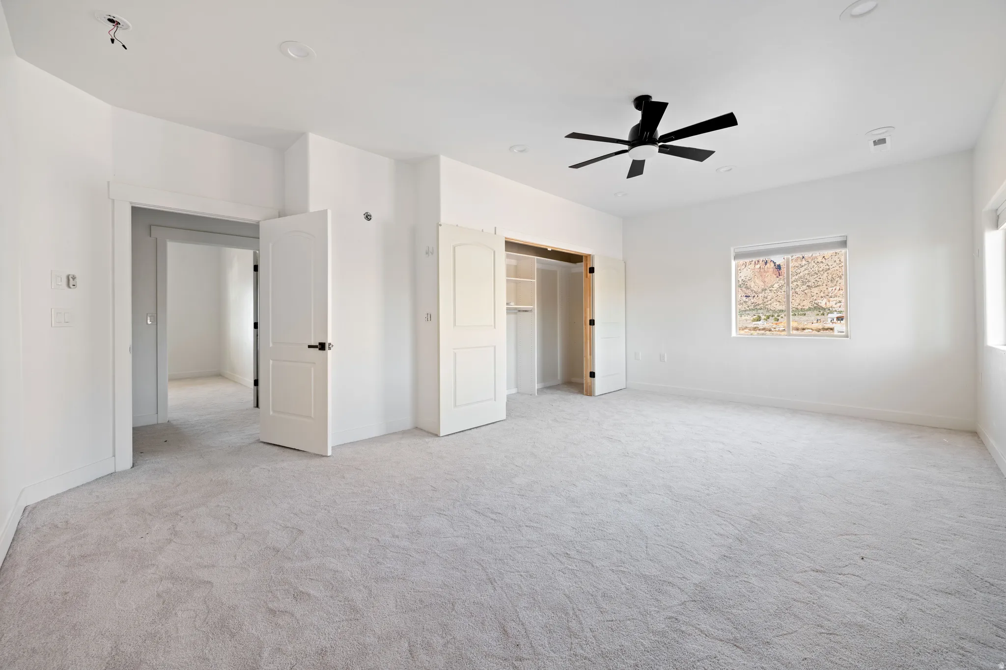 Unfurnished bedroom with light colored carpet and a ceiling fan