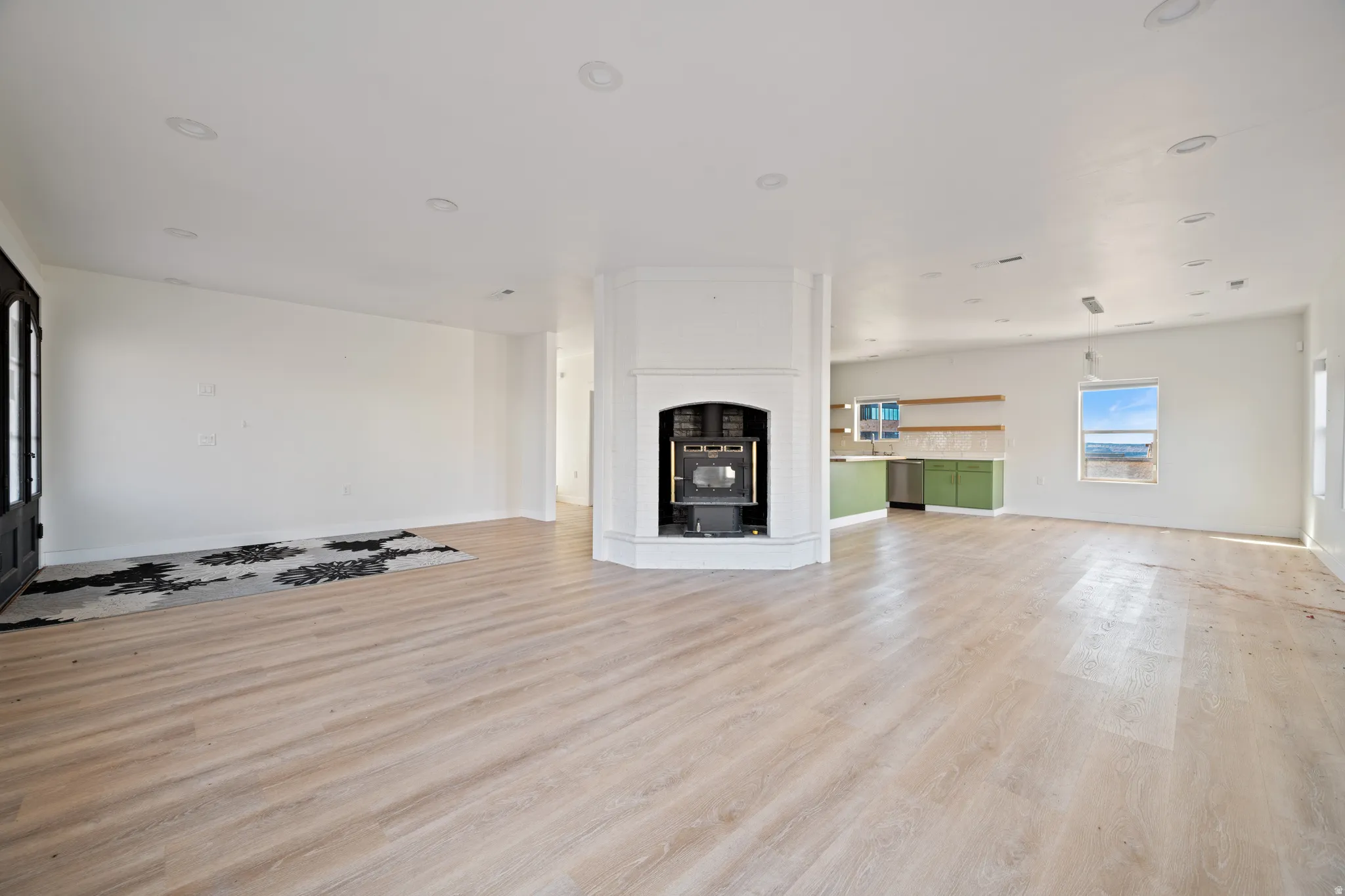 Unfurnished living room featuring light wood-style floors, a fireplace with raised hearth, and recessed lighting