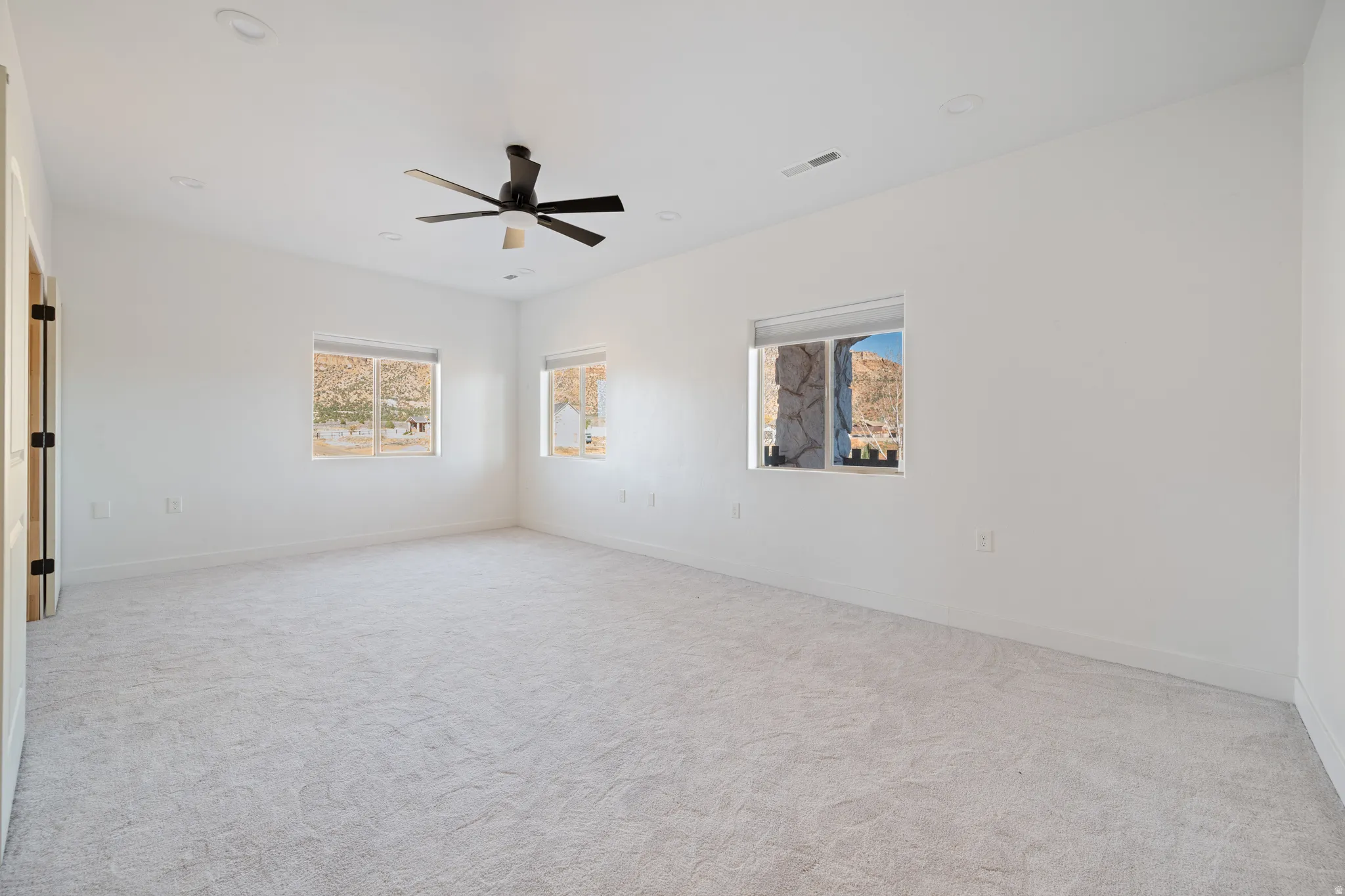 Unfurnished room featuring light carpet, a ceiling fan, and recessed lighting