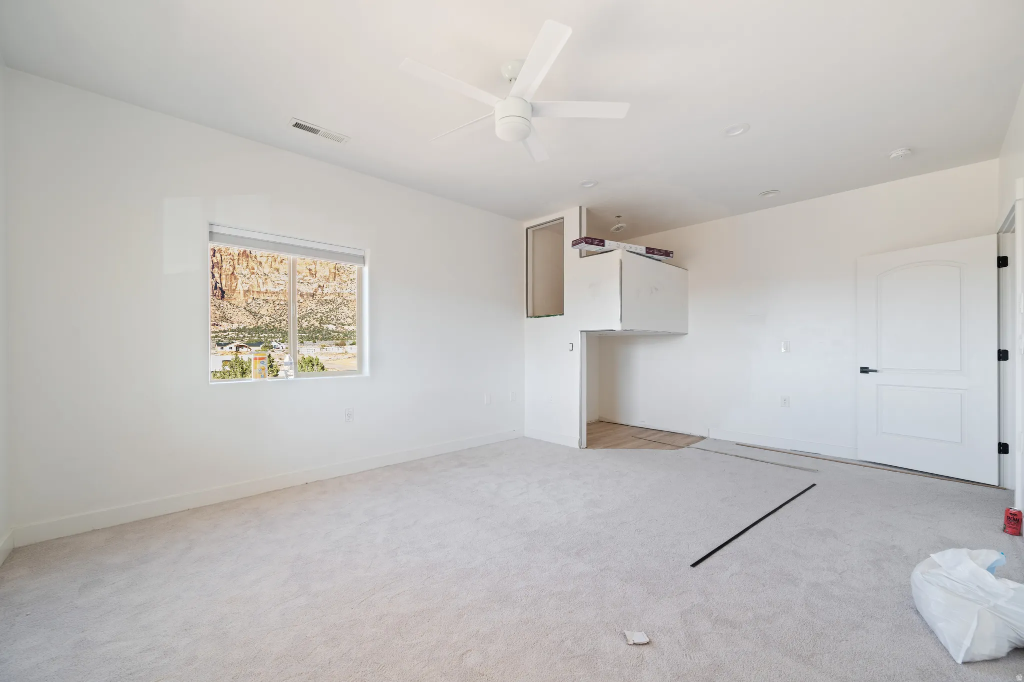 Unfurnished living room with light carpet and ceiling fan