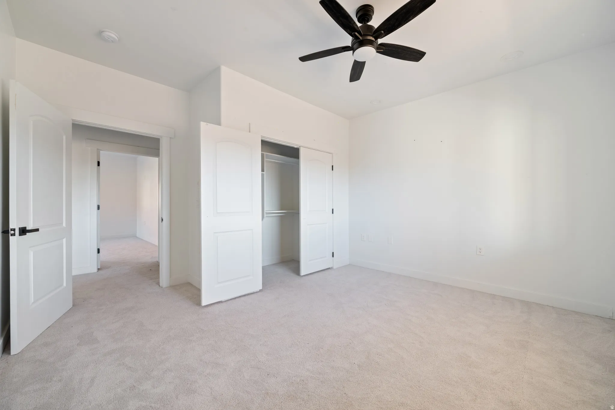 Unfurnished bedroom featuring light carpet, a ceiling fan, and a closet