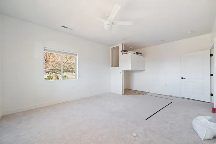 Unfurnished living room with light carpet and ceiling fan
