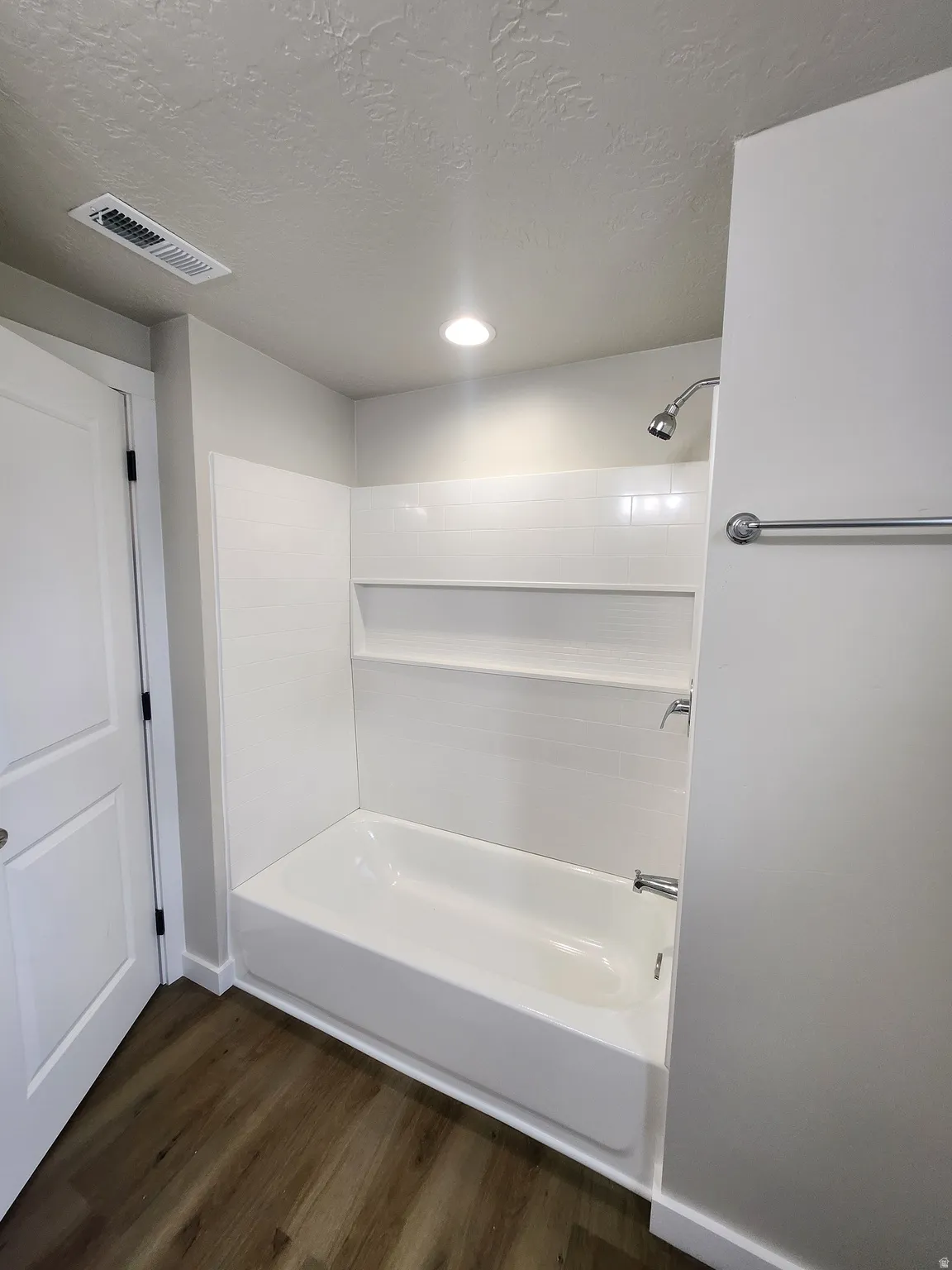 Bathroom featuring dark wood-style floors, shower / bathtub combination, and a textured ceiling