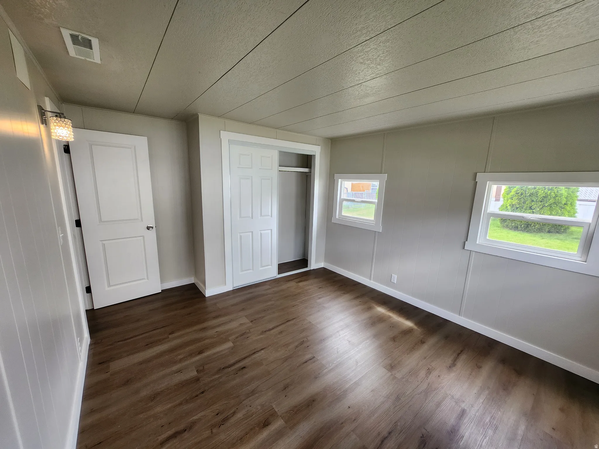 Unfurnished bedroom with dark wood-type flooring, a closet, and a textured ceiling