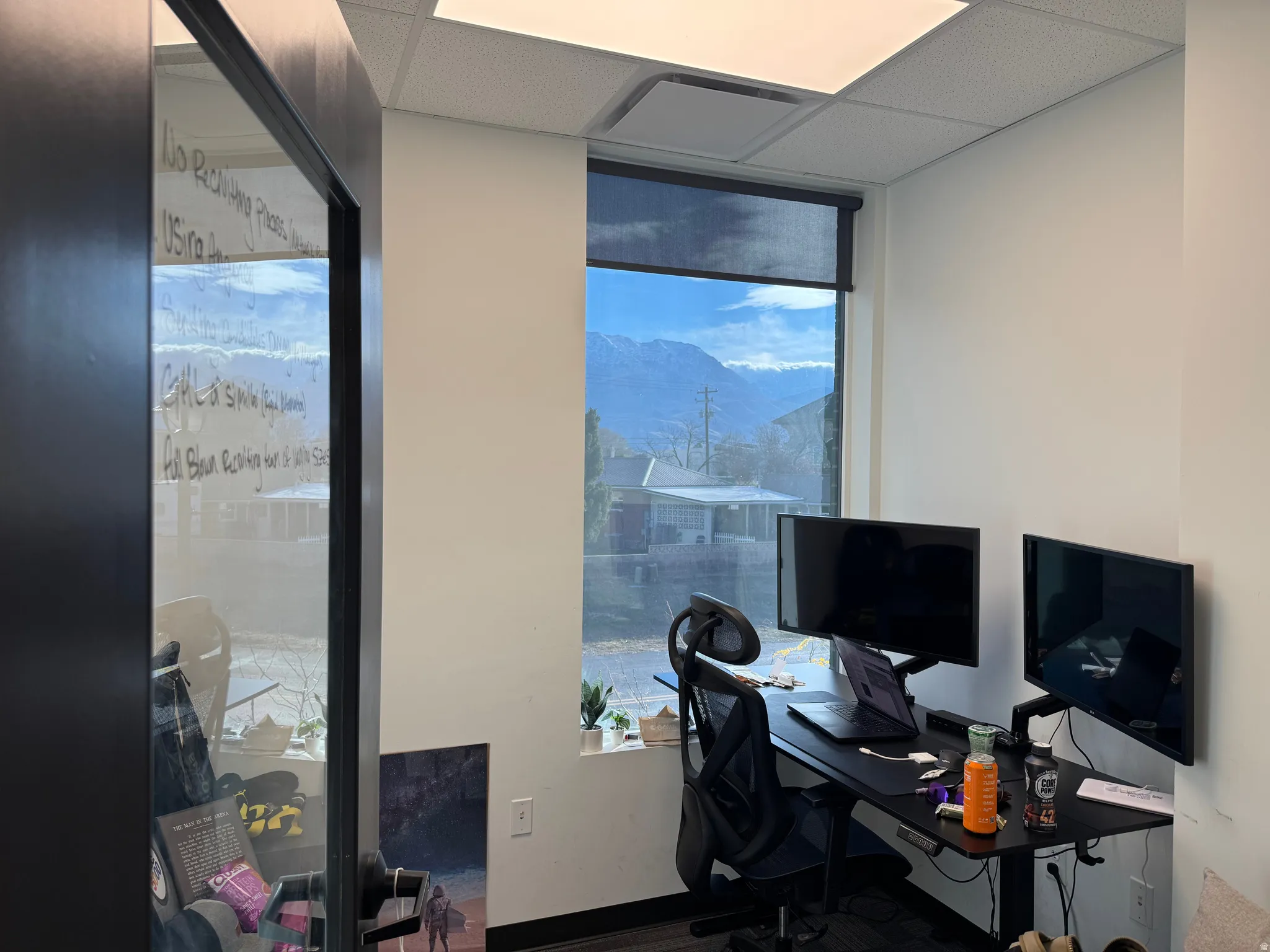 Office area featuring wood finished floors, expansive windows, and a drop ceiling