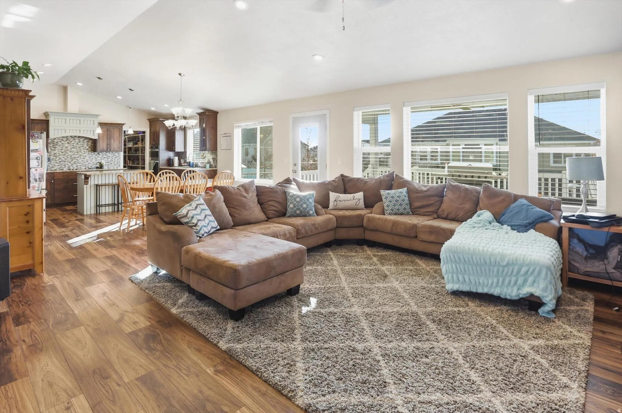 Living area featuring lofted ceiling, a chandelier, dark wood-type flooring, and recessed lighting