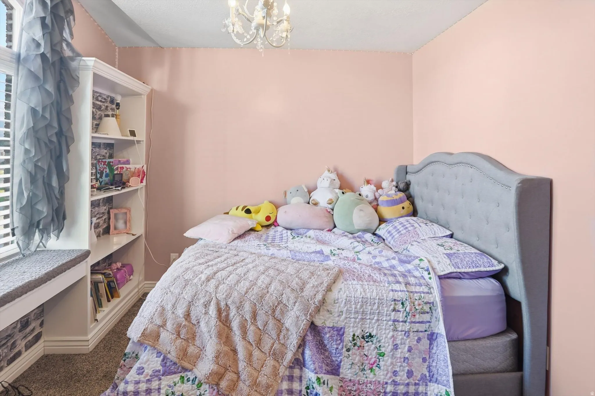 Carpeted bedroom with a chandelier and baseboards