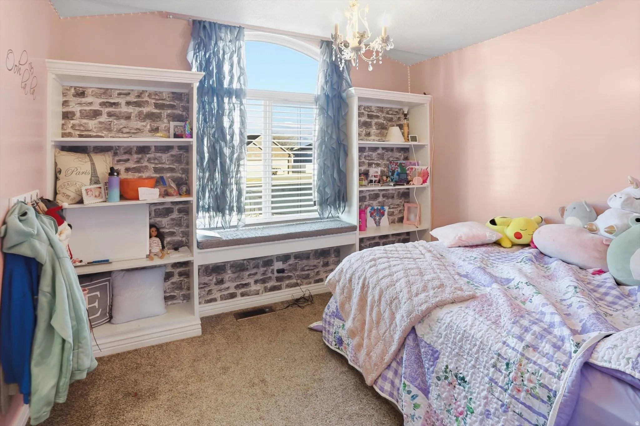 Bedroom with light colored carpet and a chandelier