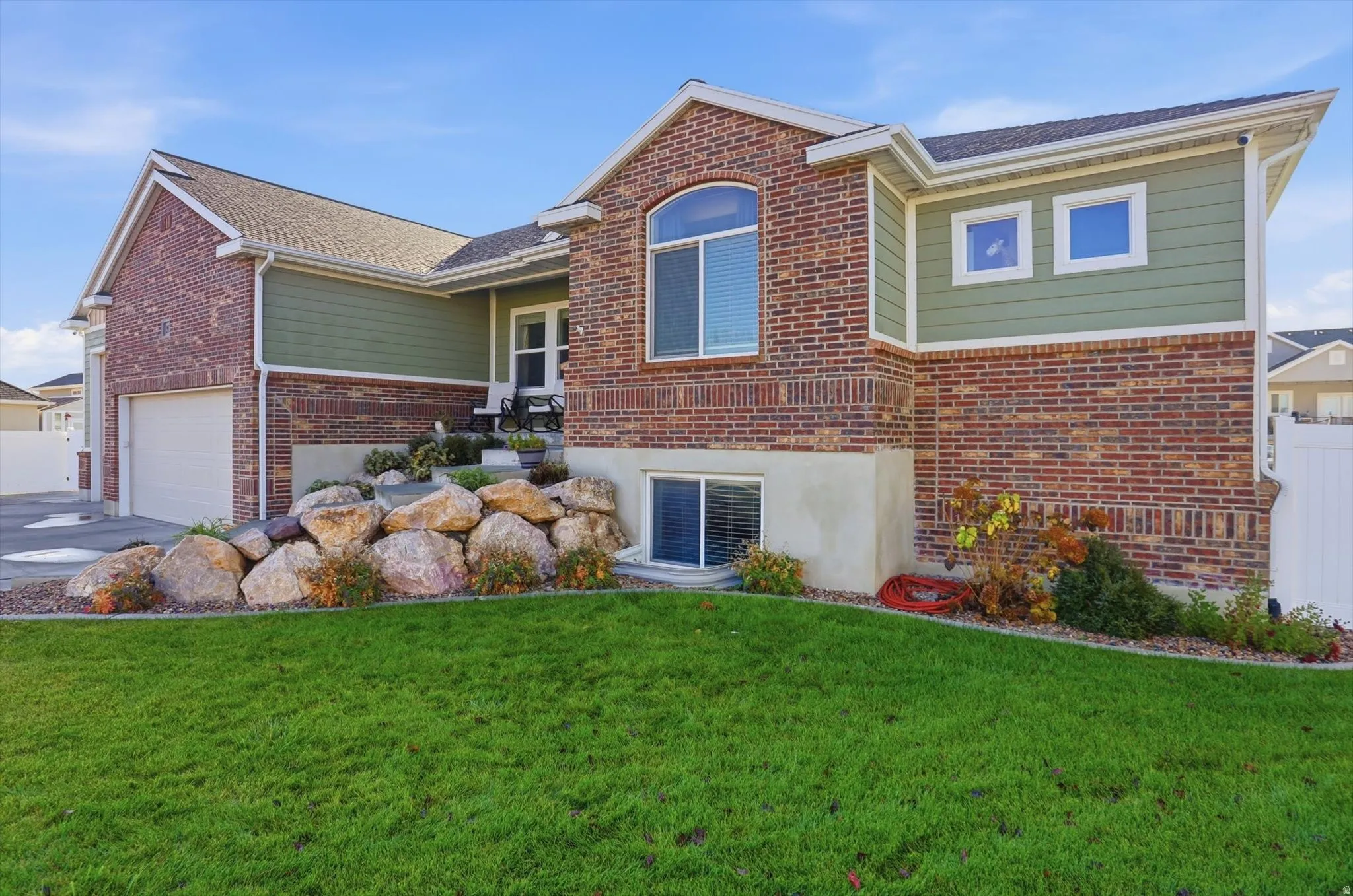 View of front of property with a front lawn, brick siding, driveway, and an attached garage