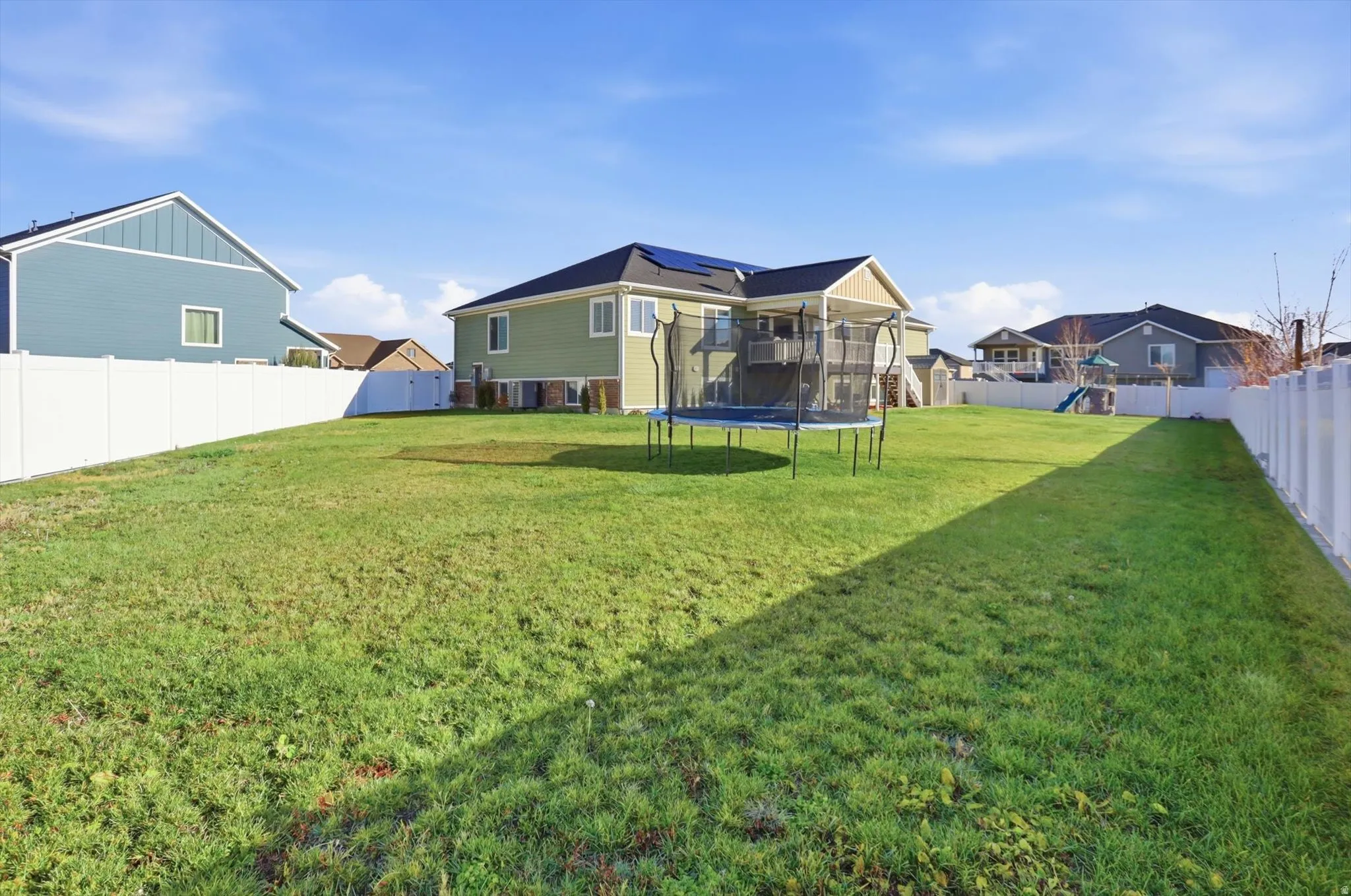 Back of house featuring a trampoline and a fenced backyard