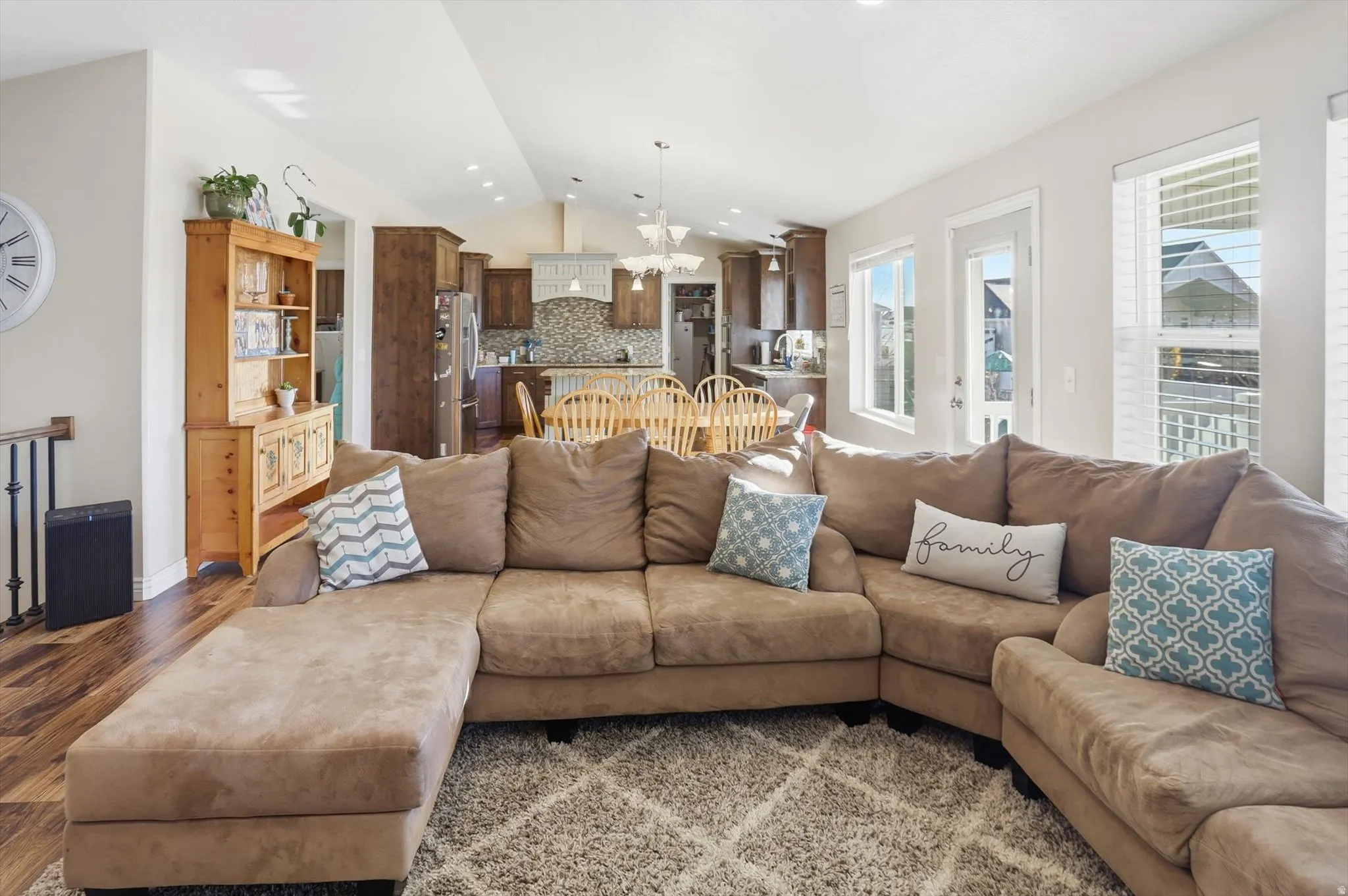 Living area featuring a chandelier, vaulted ceiling, wood finished floors, and recessed lighting