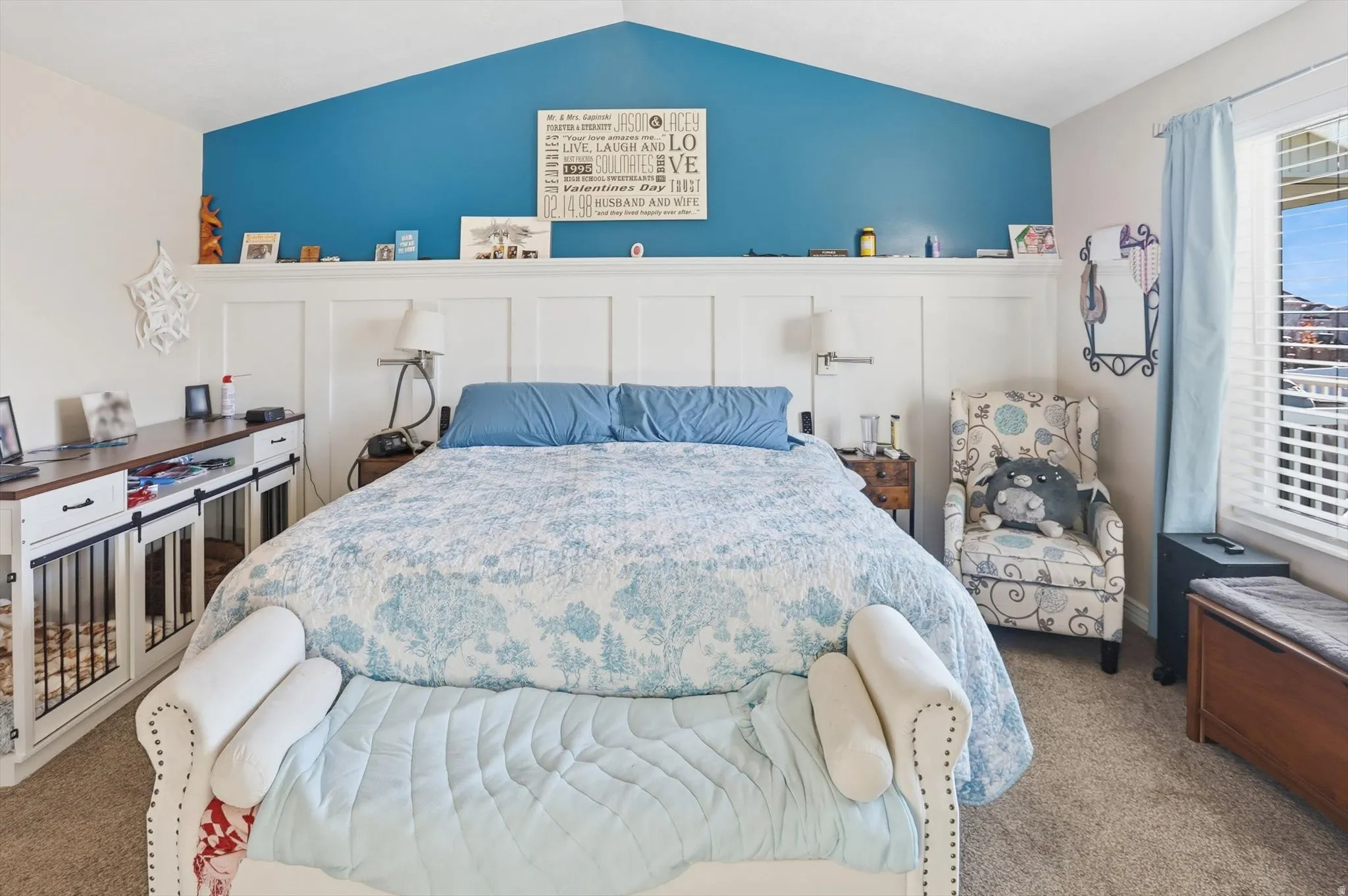 Bedroom featuring carpet floors, lofted ceiling, and a decorative wall