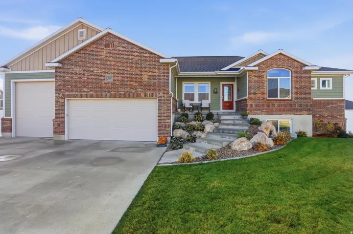 View of front of home featuring a front lawn, an attached garage, driveway, brick siding, and roof with shingles