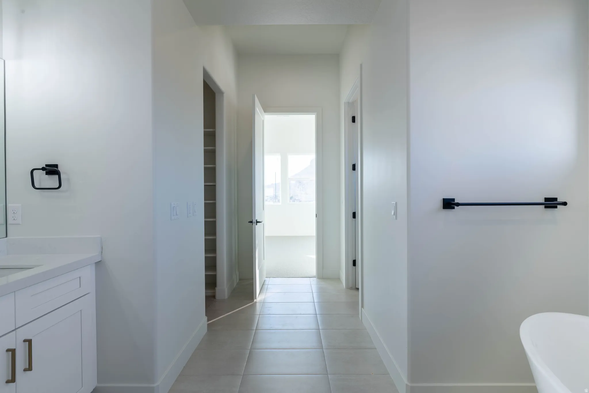Bathroom with vanity, light tile patterned floors, a spacious closet, and a freestanding bath