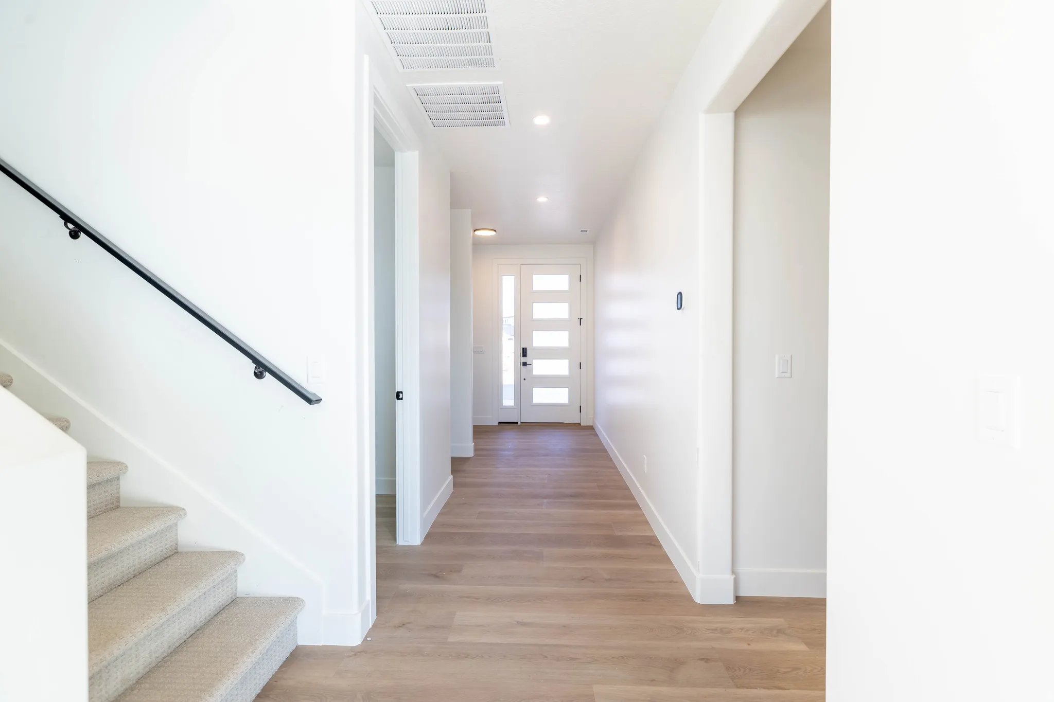 Hallway with stairs, light wood-style flooring, and recessed lighting
