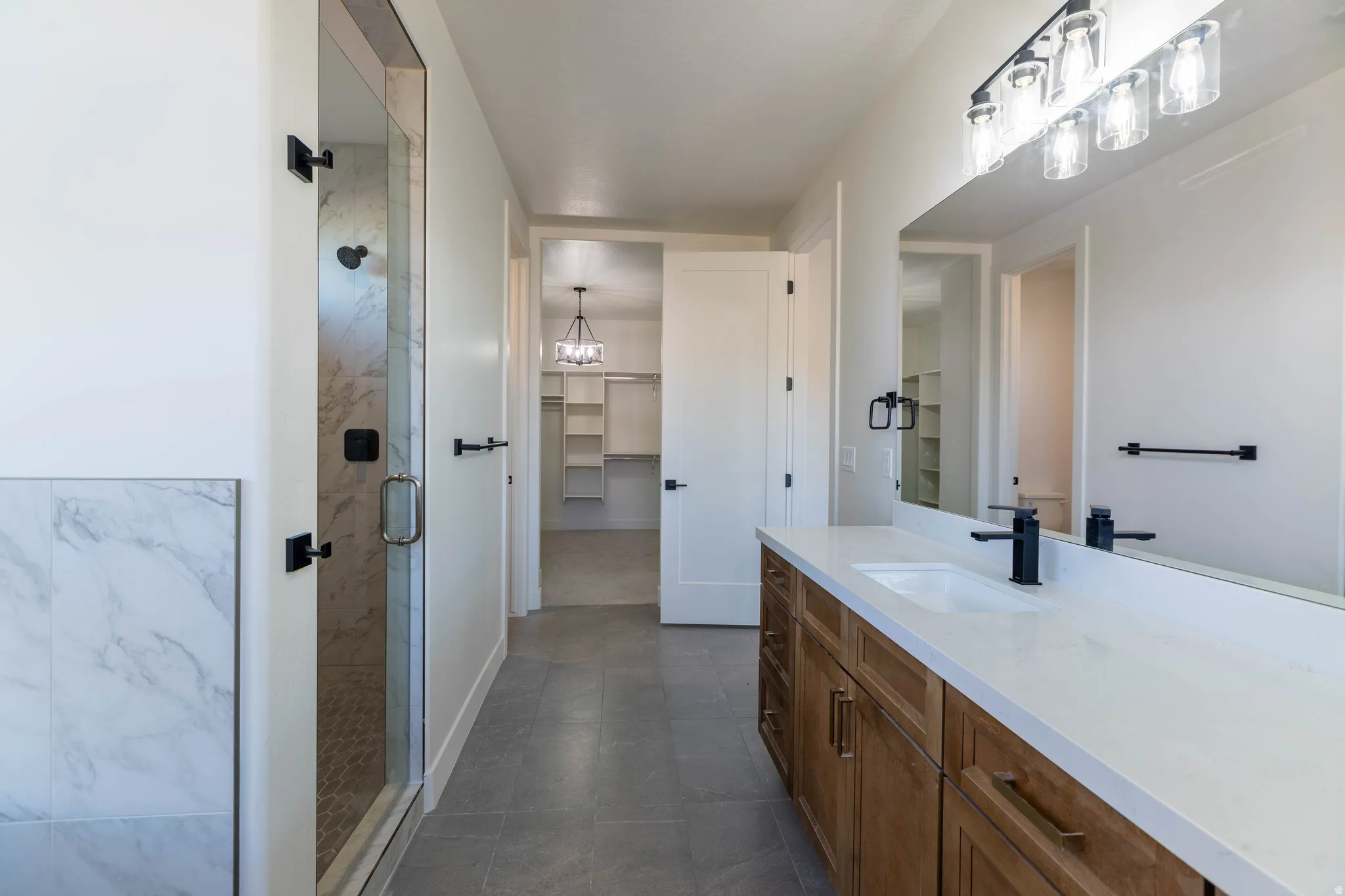 Full bathroom with vanity, a spacious closet, and a marble finish shower