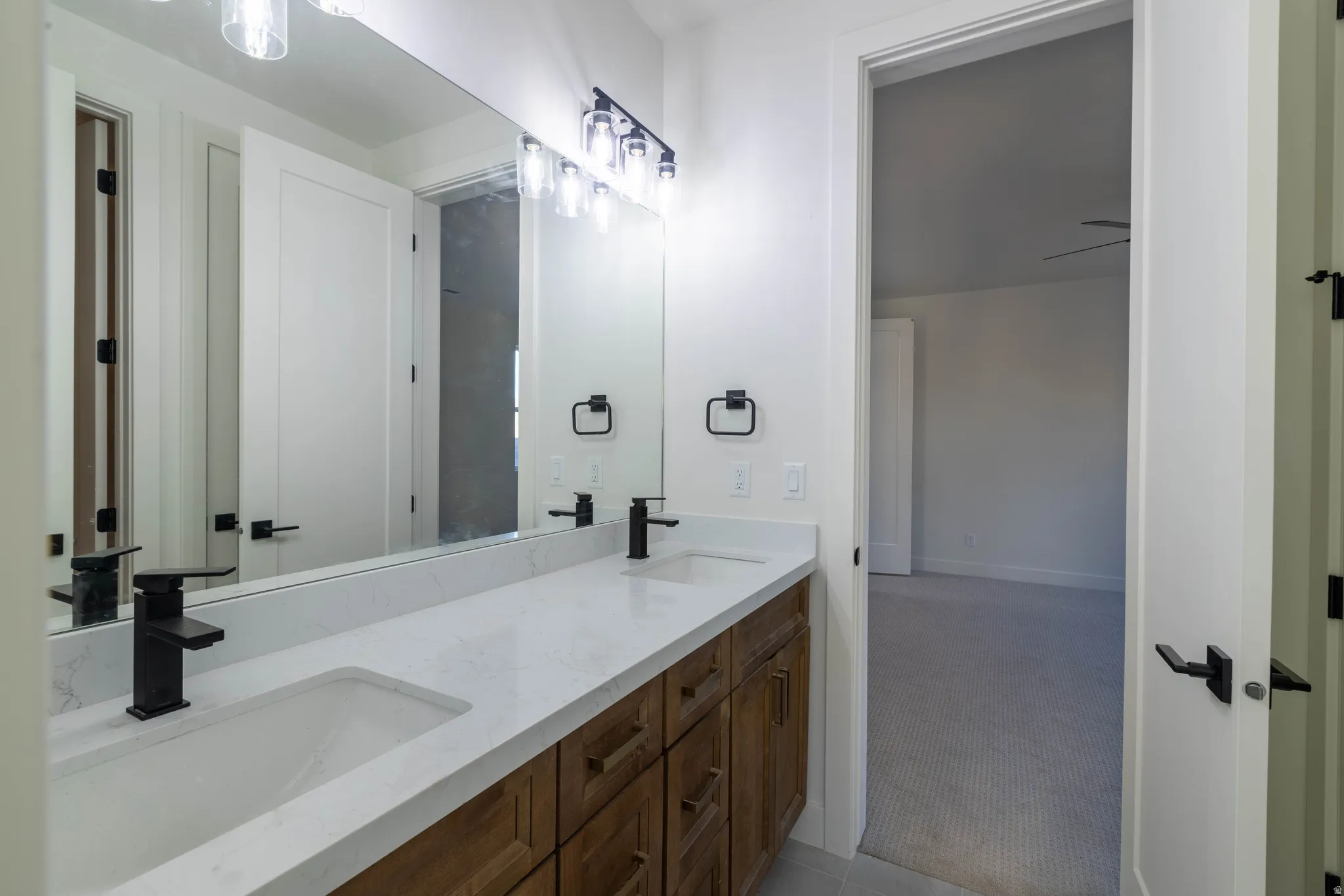Full bath featuring double vanity and light carpet