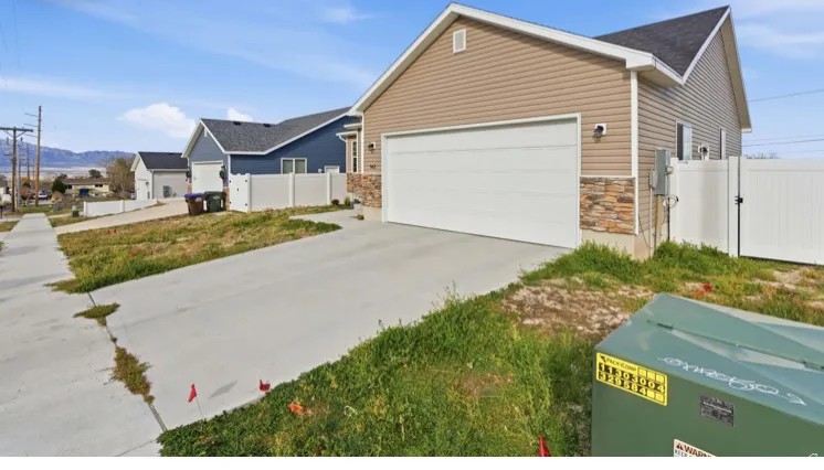 View of front of home with stone siding, a gate, concrete driveway, and an attached garage