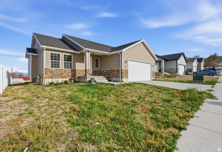 Ranch-style house with concrete driveway, covered porch, stone siding, and a garage