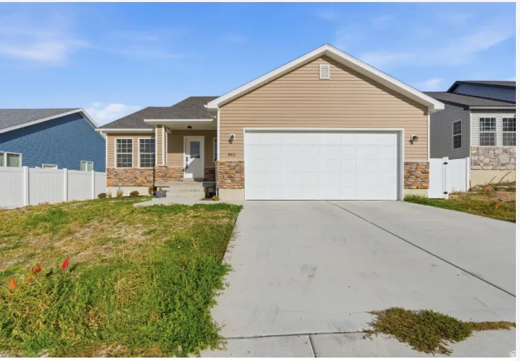 Ranch-style house featuring stone siding, driveway, and a garage
