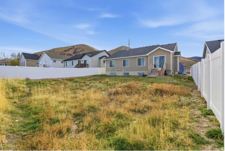 Rear view of house featuring a fenced backyard and a mountain view