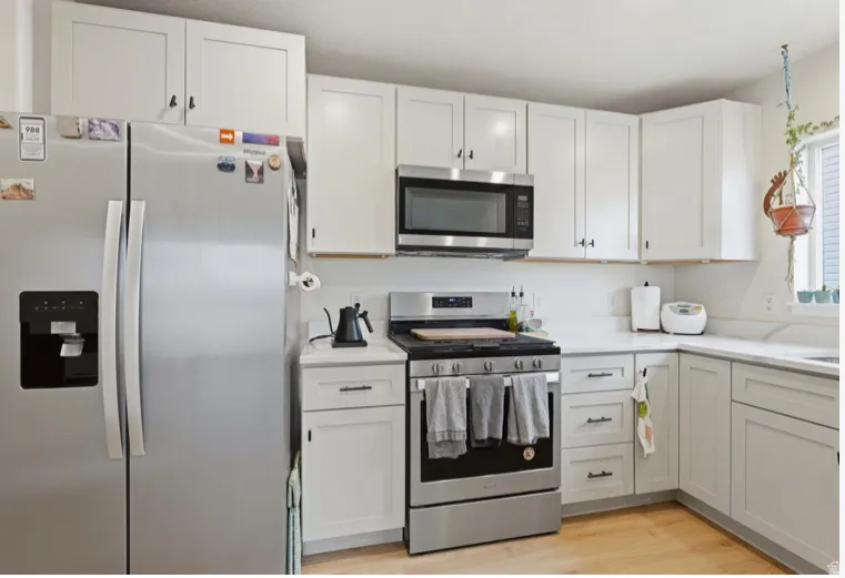 Kitchen featuring appliances with stainless steel finishes, white cabinetry, and light wood-style floors