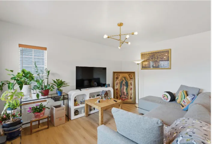 Living area with light wood-style flooring, a chandelier, and a baseboard heating unit