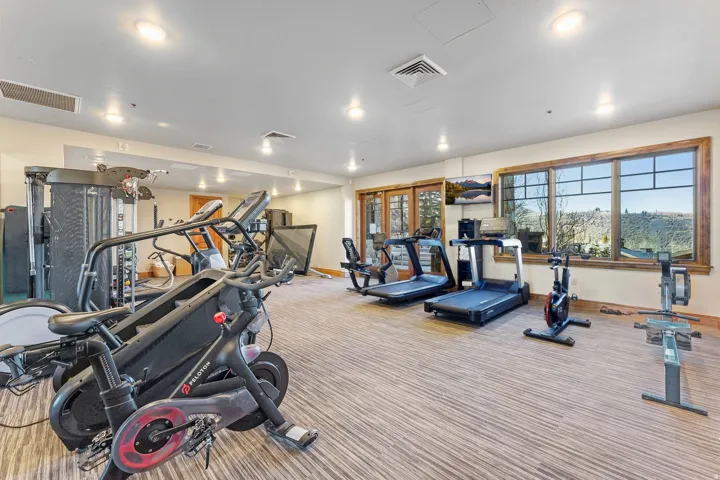 Dedicated fitness area featuring a variety of exercise equipment including stationary bikes, treadmills, and a rowing machine