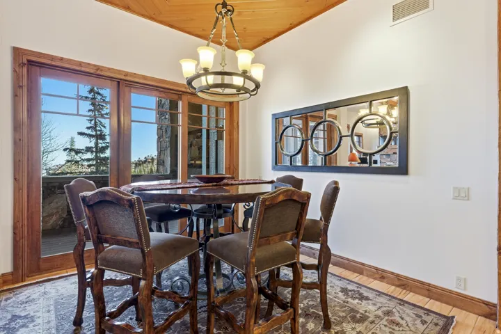 Dining area featuring wood-finish flooring, a wood-paneled ceiling, and a multi-pane glass door leading to an outdoor space